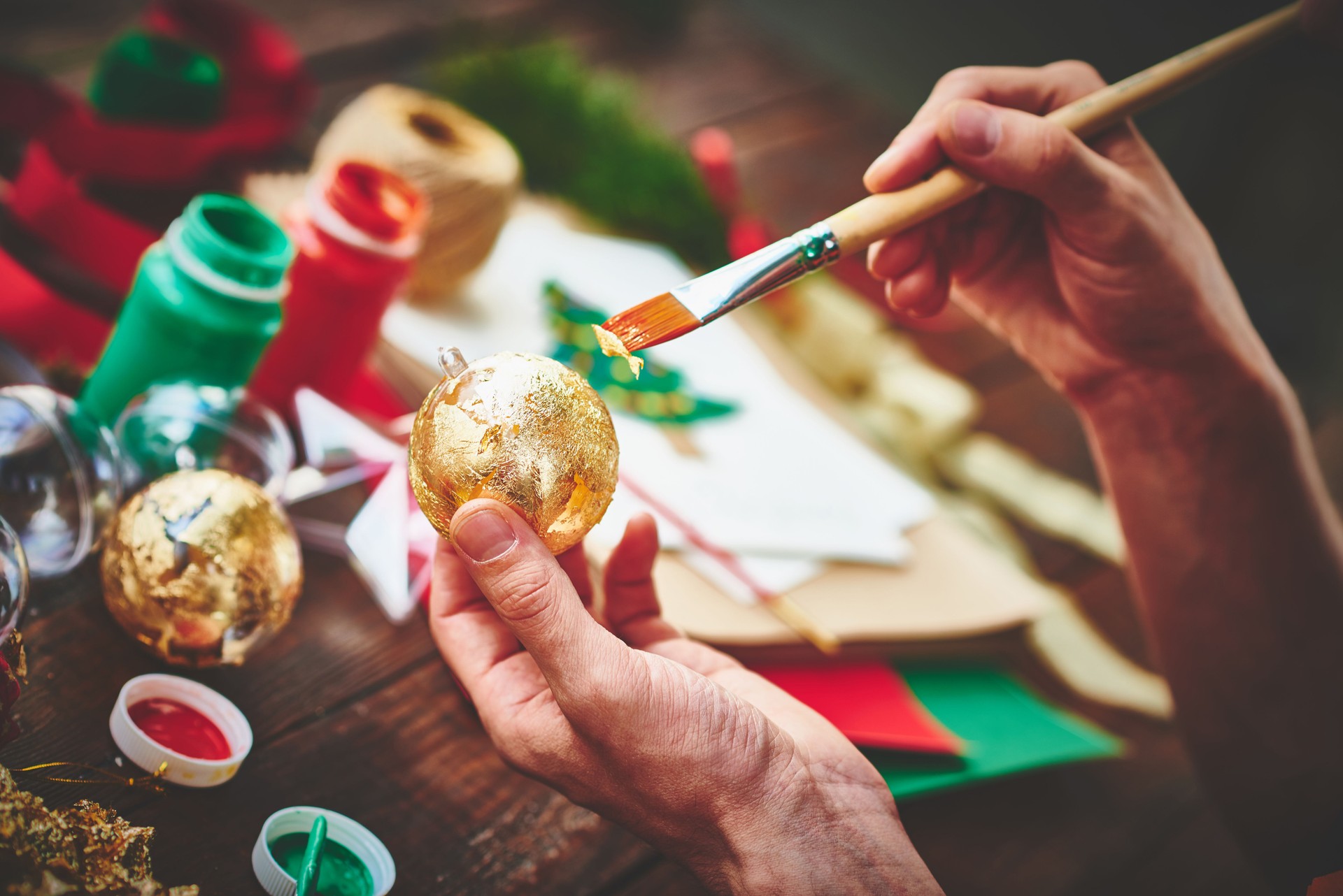 Male hands covering Christmas ornament with gold foil